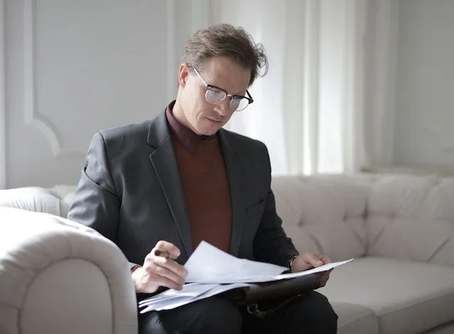 a person sitting on a sofa reading papers